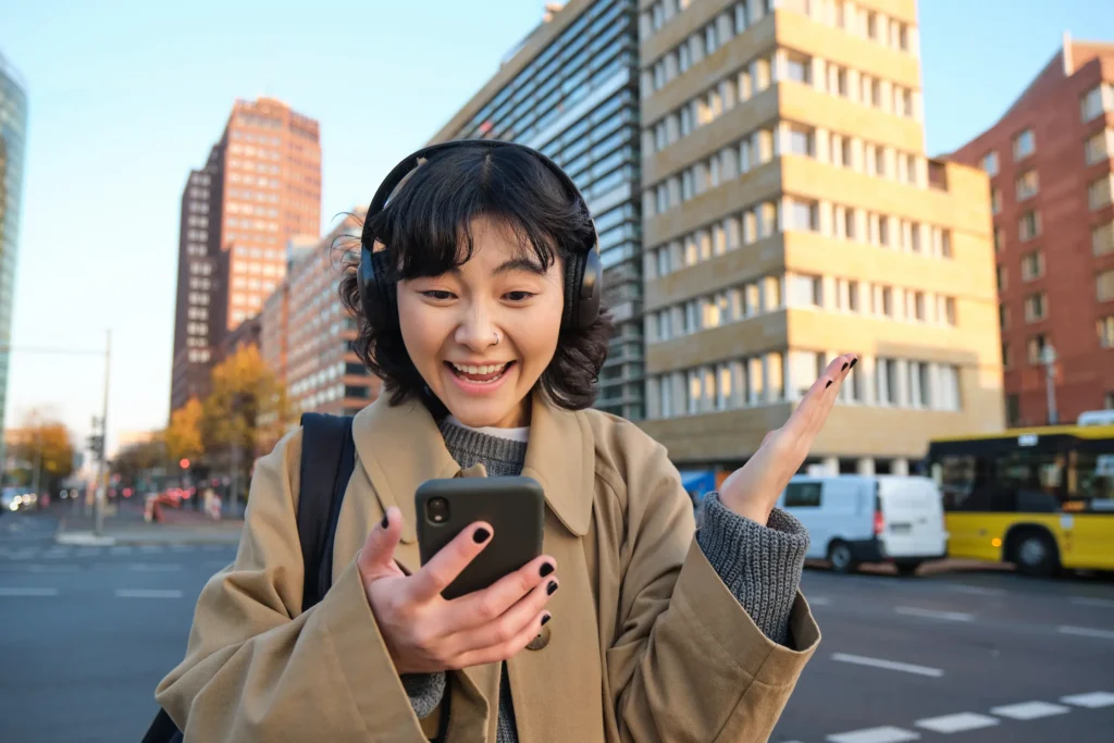 young-happy-woman-celebrating-street-holding-smartphone-cheering-reacts-amazed-good-news-r